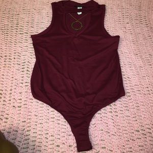 Maroon body suit with a gold/black necklace